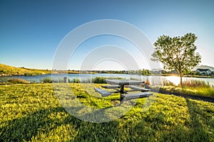 Picnic table at a park with scenic view of a lake that reflects the sky and sun