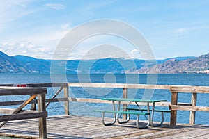 Picnic table on pier in Naramata with scenic view of Okanagan Lake and mountains