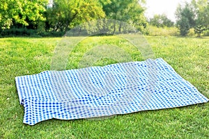 Picnic tablecloth on grass outdoor meal background.Food advertisement design backdrop empty space.Checkered cloth