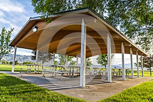 Picnic tables and benches under a pavilion on a scenic park on a sunny day