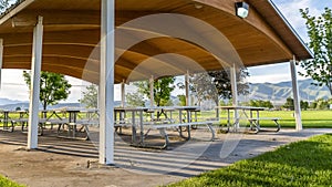 Picnic tables and benches under a pavilion on a scenic park on a sunny day