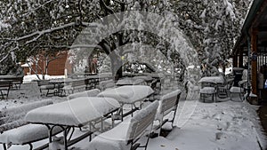 Picnic tables covered with snow at empty cafe
