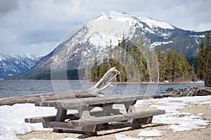 Picnic tables on winter beach of mountain lake