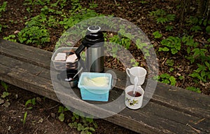 Picnic, teacup, meatbread, thermos on a wooden bench