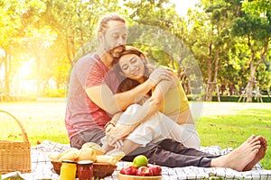 Picnic time. Happy couple relaxing on blanket enjoying picnic in sunny garden. Love and tenderness, dating, romance. Lifestyle