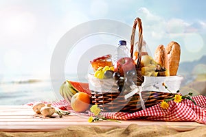 Picnic wicker basket with food on table on the beach