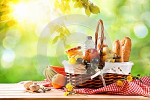 Picnic wicker basket with food on table in the field