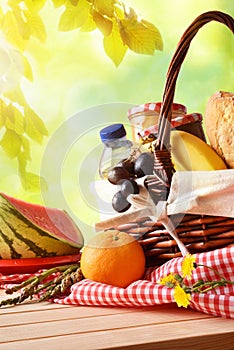 Picnic wicker basket with food on table in field vertical