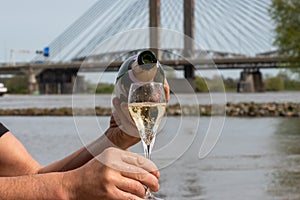 Picnic with zero alcohol sparkling wine and view on Martinus Nijhoff bridge across the Waal river near Zaltbommel in the