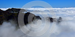 Pico do Areeiro Madeira peaks above the clouds with blue sky above.