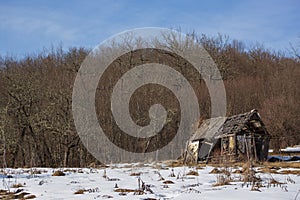 Pictorial landscape old dilapidated wooden small house stands alone in clearing with snow in mountains