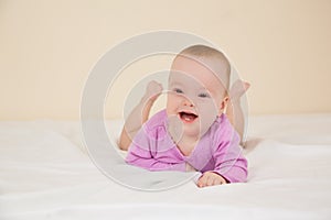 Picture of adorable baby in violet bodysuit lying on bed