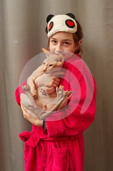 Picture of adorable young Caucasian female hugging her cute highbred pet. Sphynx cat with no fur purring in arms