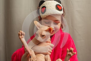 Picture of adorable young Caucasian female hugging her cute highbred pet. Sphynx cat with no fur purring in arms