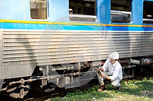 Picture of Asian engineer wearing safety helmet with checking train for maintenance in station