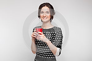 Picture of attractive woman in speckled clothes standing with cup in hands