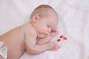 Picture of baby sleeping on the blanket with three pills