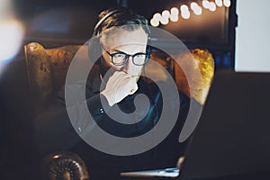 Picture bearded man wearing glasses working modern loft office. Young banker sitting vintage chair,listening music