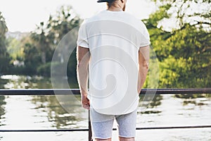 Picture Bearded Muscular Man Wearing White Blank t-shirt, snapback cap and shorts in summer time. Relaxing time near the