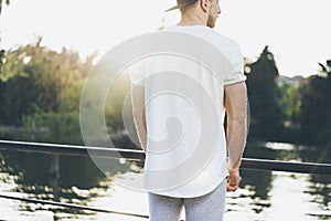 Picture Bearded Muscular Man Wearing White Blank t-shirt, snapback cap and shorts in summer vacation. Relaxing time near