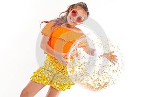 Picture of a beautiful caucasian girl with sunglasses and holds a big nflatable wound-coloured ball, isolated on white