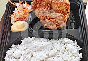 A picture of a bento box consist of rice and fried chicken with salad