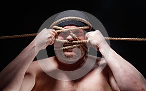 Picture of binded fat man in cap with rope on face