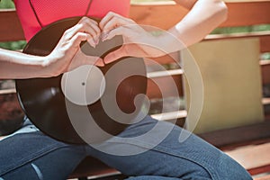 A picture of black vynil leaning to girl`s body. She is sitting on bench and crossing her legs. Girl is shwoing the love