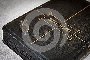 Picture of a book Bible close-up in black leather binding with a zipper with a Christian pendant symbol fish on a gray background