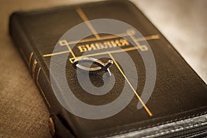 Picture of a book Bible close-up in black leather binding with a zipper with a Christian pendant symbol fish on a gray background