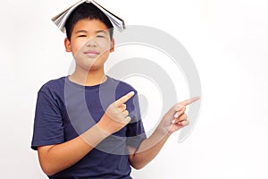 A picture of a boy in glasses point to the side and covering his head with a book. Education concept