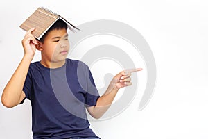 A picture of a boy in glasses point to the side and covering his head with a book. Learning concept