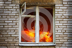 Picture of brick house with with fire in window.