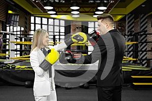 Picture of a businessman and a businesswoman sparring with boxing gloves against of a boxing ring