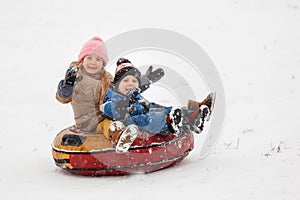 Picture of cheerful sister and brother riding tubing