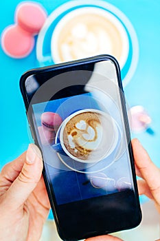 Picture of a coffee on a smartphone on a blue table.