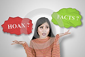 Confused woman choosing a word of hoax or fact photo