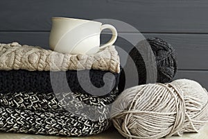 Picture of cozy sweaters and cup of coffee or tea over grey back