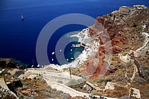 Deep blue sea and steep red mountain with a serpantine road. Santorini Island, Greece photo