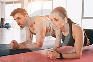 A picture from a different angle where two beautiful people are wokring out and using a plank position for that. Both of