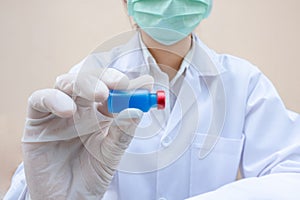 The picture of doctor`s hand is holding a blue vaccine tube