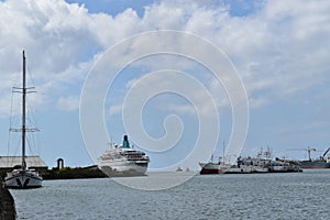 Picture of the entrance of a port with a beautiful and large sailing boat on the left