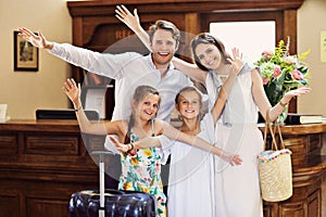 Happy family checking in hotel at reception desk