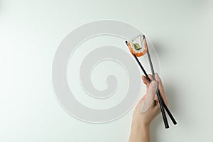 Female hand hold chopsticks with roll on white background