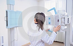 picture of a female radiologist adjusting the X-ray machine in examination rom