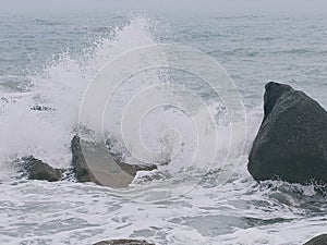 A picture of the force of wave collision with beach rocks.