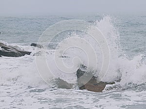 A picture of the force of wave collision with beach rocks.