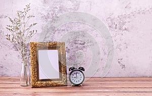 Picture frame and flowers and clock on wooden table. Poster product design styled