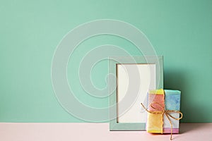 Picture frame and gift box on pink table. mint green wall background. copy space