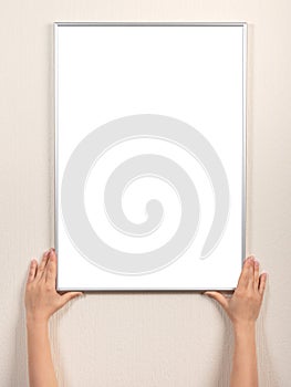 Picture frame of hand is hanging on the wall. woman hanging blank posteron wall. diploma mockup